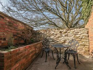 two chairs and a table in front of a brick wall at Top Holme Cottage in York