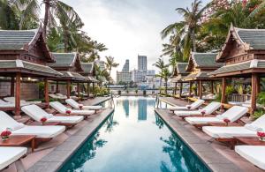 a pool at the resort with chaise lounge chairs at The Peninsula Bangkok in Bangkok