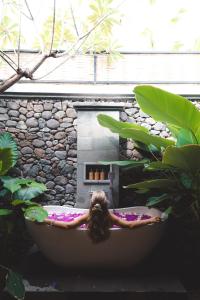 a woman in a bath tub in a garden at Sumberkima Resort in Pemuteran