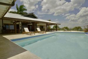 a swimming pool with two chairs next to a house at Villa Lukner Las Terrenas in Las Terrenas