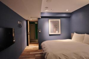 a bedroom with a blue wall with a bed at Happy Inn in Taichung