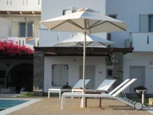 a white umbrella and chairs next to a pool at Roses Beach in Parikia
