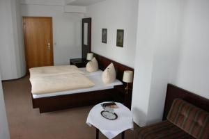 een slaapkamer met een bed, een tafel en een stoel bij Hotel Diening in Essen