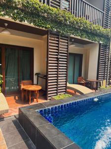 a swimming pool next to a house with a table at BB Mantra Boutique Hotel in Chiang Mai