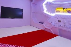 a room with a red and white bed and a tv at Hotel O Fiducia Capsule Hotel in Jakarta +19 photos