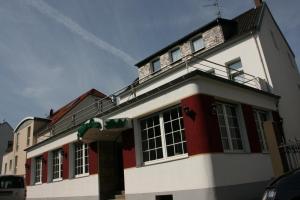 een groot wit en rood huis met een balkon bij Hotel Diening in Essen