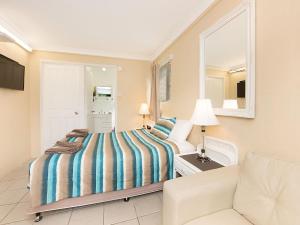 a hotel room with a bed, chair, and nightstand at Caloundra City Centre Motel in Caloundra