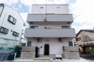 a tall white building with a grey roof at BALOH Wadamisaki in Kobe