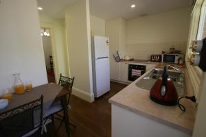 a kitchen with a table and a white refrigerator at Annies Garden Cottage in Hobart