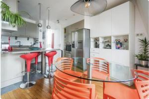a kitchen with a glass table and red chairs at Sweet home in Paris