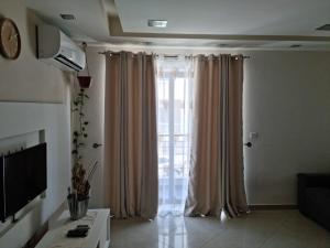 una sala de estar con una gran ventana con cortinas en Southern Court Apartment, en Il-Ħamrija 9 fotos más