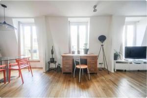 a living room with a table and a desk with a television at Sweet home in Paris