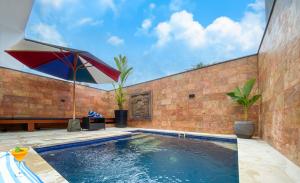 a swimming pool with an umbrella next to a brick wall at Winy Home Lovina in Lovina
