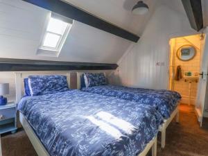 a bedroom with a bed with a blue comforter at Roseberry Cottage in Whitby
