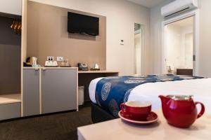 Una habitación de hotel con una cama y una mesa con una taza en Leumeah Lodge en Canberra