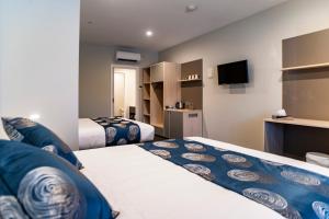 Habitación de hotel con 2 camas y TV en Leumeah Lodge en Canberra