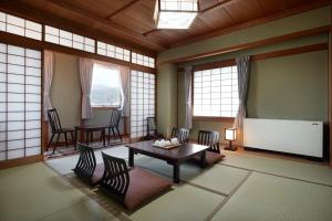松本市にある松本ホテル花月のテーブルと椅子、スクリーンが備わる客室です。