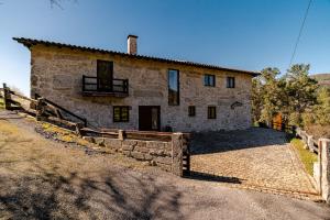 a stone house with a fence in front of it at Turismo Rural No Gerês in Carvalheira