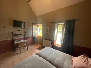 a bedroom with a bed and a table and two windows at Domaine de Collen in Lépine