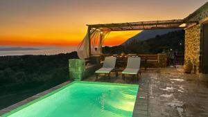 a swimming pool with chairs and a sunset in the background at Cassiopea Guest House Evia Greece in Nerotriviá