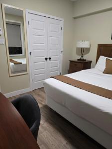 a bedroom with a bed and a chair and a mirror at Cozy Maison Apt #8 in Gatineau