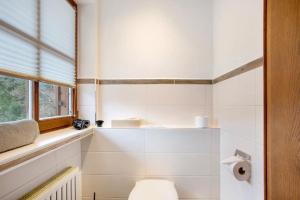 a white bathroom with a toilet and a window at Gästehaus Panorama - Appartement 2 in Reit im Winkl