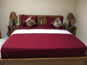 a bedroom with a large red bed with two lamps at Jessies beach house in Pulau Lutung +16 photos