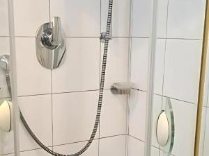 une douche avec un tuyau fixé à un mur carrelé blanc dans l'établissement Apartment Vintage, à Sankt Martin 13 autres photos