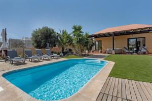 Una piscina en un patio con sillas y una casa. en El refugio, en La Oliva