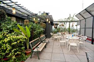 an outdoor patio with tables and chairs and plants at Well Park Residence Boutique Hotel & Suites in Chittagong