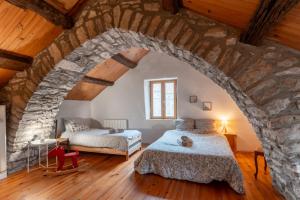 a bedroom with two beds and a stone wall at Maison de village au cœur des remparts in Sainte-Eulalie-du-Cernon