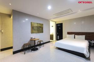 a bedroom with a white bed and a table and stool at Ignis Hotel busan sports complex branch in Busan