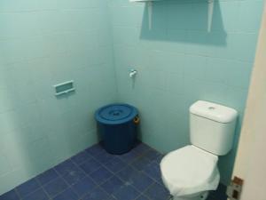 a bathroom with a toilet and a blue trash can at Palm Cozy Villa in Pasauran