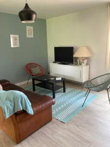Una sala de estar con un sofá y un televisor. en La Chamade gîte Albi, en Terssac