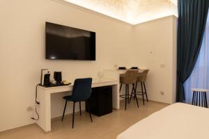 a room with a bed and a desk with a television on the wall at Dimora Zonno in Bari