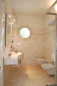 een badkamer met een wastafel, een toilet en een spiegel bij Hotel Castello in Modena