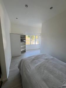 a white bedroom with a bed and a window at Appartement calme et paisible au bord de la rivière in Ernée