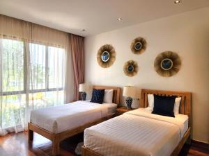 two beds in a bedroom with mirrors on the wall at WEG Laguna Residence in Thalang +18 photos