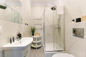a white bathroom with a shower and a sink at Apartament 06 Blisko Plaży z Ogrodem - Grzybowo, Kołobrzeg - Nadmorska 26 in Grzybowo