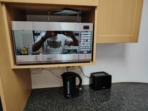a microwave in a kitchen with a man taking a picture at Pennington Beach Cottage Holiday accommodation in Pennington +10 photos