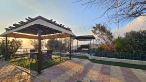 a pavilion with a table and umbrella on a patio at بيت الشرف للضيافة Sharaf Guest in Al Ḩamrāʼ