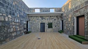 a large stone building with a wooden floor at بيت الشرف للضيافة Sharaf Guest in Al Ḩamrāʼ
