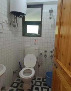 Un baño con inodoro, lavabo y ventana. en Hotel Ved Bageshwari, en Chhatikara