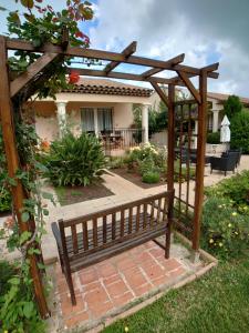 a wooden bench in a garden with a pergola at L'orangerai d'Antibes in Antibes