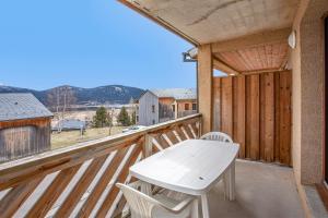 einen Holzbalkon mit einem weißen Tisch und Stühlen darauf in der Unterkunft L'Escapade aux Angles - Proche Stations in Les Angles