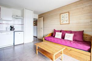 ein Wohnzimmer mit einem lila Sofa und einem Tisch in der Unterkunft L'Escapade aux Angles - Proche Stations in Les Angles