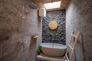 e bagno con vasca in un muro di pietra. di The Macaw Ubud Green Uma Villa a Blahbatu