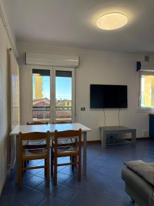a living room with a table and chairs and a television at App4rent - VILLA MIMOSA - 3 Family apartments - parking, wifi, near the beach in Lido di Jesolo +50 photos