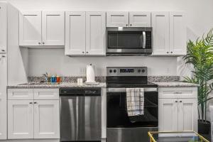 a kitchen with white cabinets and a stove and a microwave at CozySuites Stunning 1BR in Downtown Pitts #21 in Pittsburgh