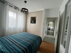 a bedroom with a bed with a blue striped blanket at Maison de vacances 6 personnes près de Bordeaux Green Escape in Cenon